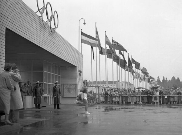 Soihtunkantaja juoksee ulos Käpylän kisakylän portista Helsingin olympialaisissa 1952-0